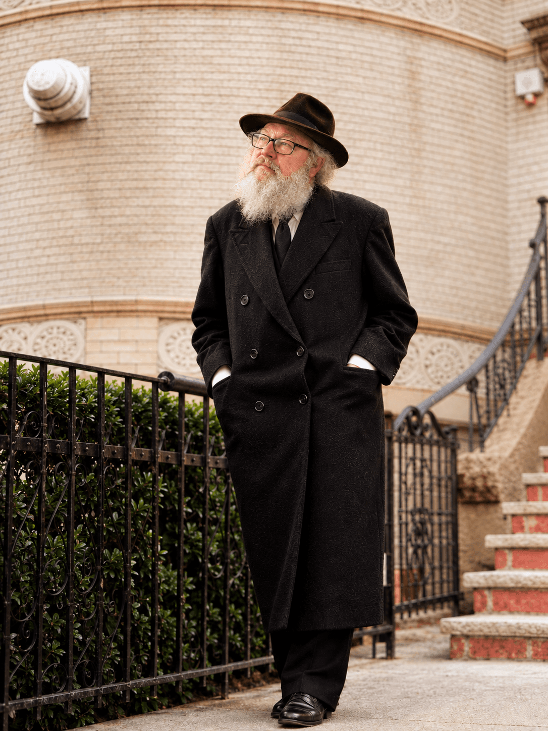 Dr. Clifford Waldman in a long dark coat and hat, standing on a New York street